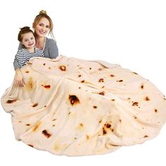 a woman and her child wrapped in a blanket on the ground with food all over them