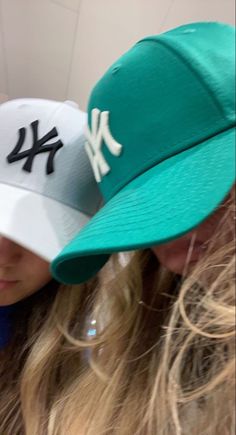 two girls wearing hats with the new york yankees on them