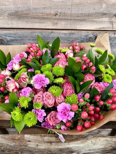 a bouquet of pink and green flowers on top of a piece of brown wrapping paper