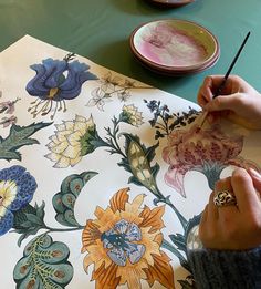 a person is painting flowers on a table