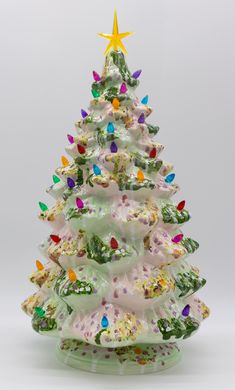 a glass christmas tree with colorful lights on it's top and the base is white