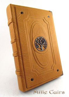 a brown book with a tree on the front cover and an embossed circle in the middle