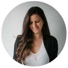 a woman with long brown hair smiling at the camera in a white circle on a white background