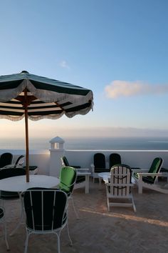 an umbrella and chairs on a patio overlooking the ocean