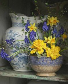 blue and white vases with yellow flowers in them on a shelf next to each other