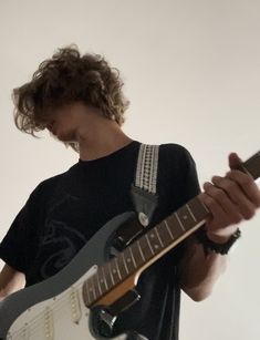 a man with curly hair playing an electric guitar