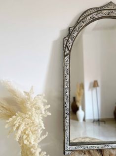 a mirror sitting on top of a wall next to a vase