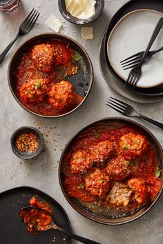 two bowls filled with meatballs covered in sauce and garnished with parmesan cheese