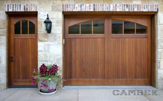 two wooden garage doors with flower pots in front