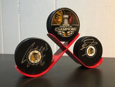 three black hockey pucks with signed autographs on them sitting on a table next to each other