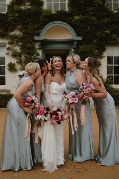 a group of women standing next to each other in front of a building with flowers