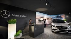 a mercedes benz showroom with two people standing in front of the car and another person looking at it