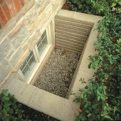 an open window sitting in the side of a brick building next to green bushes and shrubbery