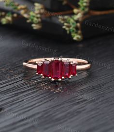 three stone ring on top of a wooden table with greenery in the back ground