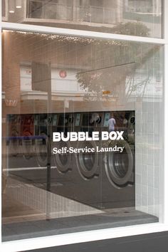 the bubble box self service laundry sign is reflected in the window