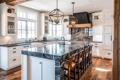 a large kitchen with an island in the middle and marble counter tops on both sides