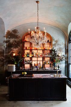 an elegant bar with chandelier and liquor bottles on the shelves in front of it