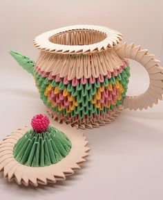 an origami teapot and cup with a strawberry on the top, sitting next to each other