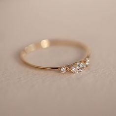 a gold ring with two diamonds on it sitting on a white tableclothed surface