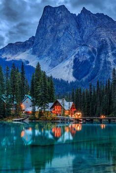 a mountain range is in the distance with houses on it and trees around it, lit up at night