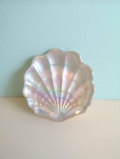 a shell shaped dish sitting on top of a white table next to a blue wall