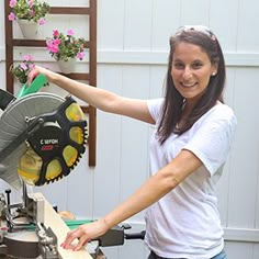 a woman holding a circular saw on top of a table