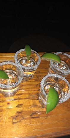 limes are placed in small glass dishes on a wooden tray