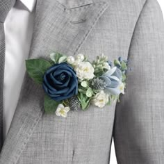 a man in a gray suit with blue and white flowers on his lapel flower