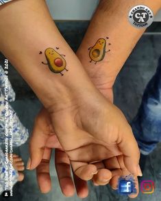 two people are holding hands with tattoos on their wrist and the other hand has an orange