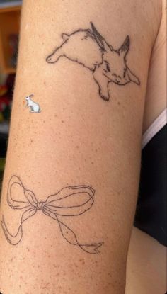 a woman's arm with tattoos on it and an image of a rabbit in the background