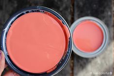 a person holding a paint can in their hand with the lid open and another container next to it