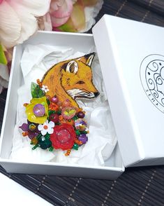 a box that has some kind of animal decoration in it's lid and is sitting on a table next to flowers