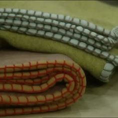 two pieces of fabric sitting on top of a table next to each other, one green and the other orange