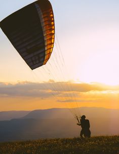 a person is flying a large kite in the sky with mountains in the back ground