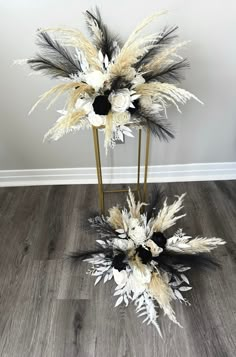 two tall white and black flowers on a metal stand in front of a gray wall