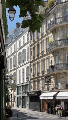 people are walking down the street in front of tall buildings with balconies on them