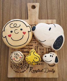 three decorated cookies sitting on top of a cutting board