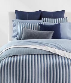 a bed with blue and white striped sheets, pillows and pillow cases on top of it