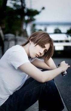 a woman sitting on top of a skateboard next to a wall with her hand on her hip