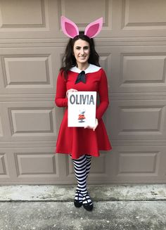 a girl dressed as an elf holding up a sign that says oliva in front of a garage door