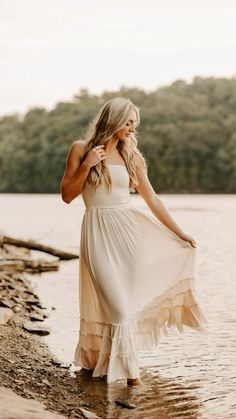 a woman standing in the water wearing a white dress