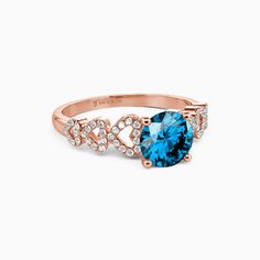 an oval blue topaz ring with diamonds on the band and side stones in rose gold