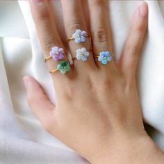 a woman's hand with three rings on it and four flowers in the middle