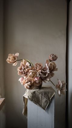 a bunch of flowers sitting on top of a wooden block in front of a window