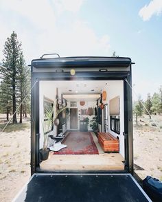 the back end of a trailer with its door open to reveal a living room and dining area