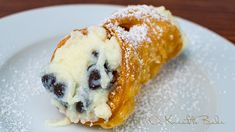 a pastry on a plate with powdered sugar and blueberries in the fillings