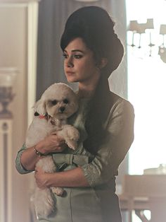 a woman holding a small white dog in her arms