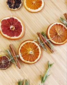 dried oranges and cinnamon sticks are arranged on a wooden table with rosemary sprigs