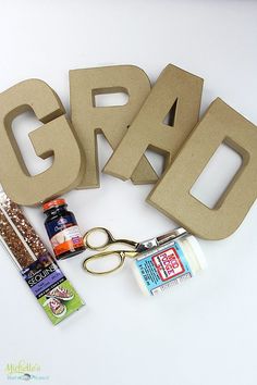 the word grad spelled out in cardboard letters with scissors and other crafting supplies