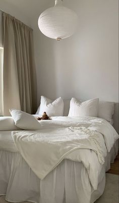 a bed with white sheets and pillows in a room